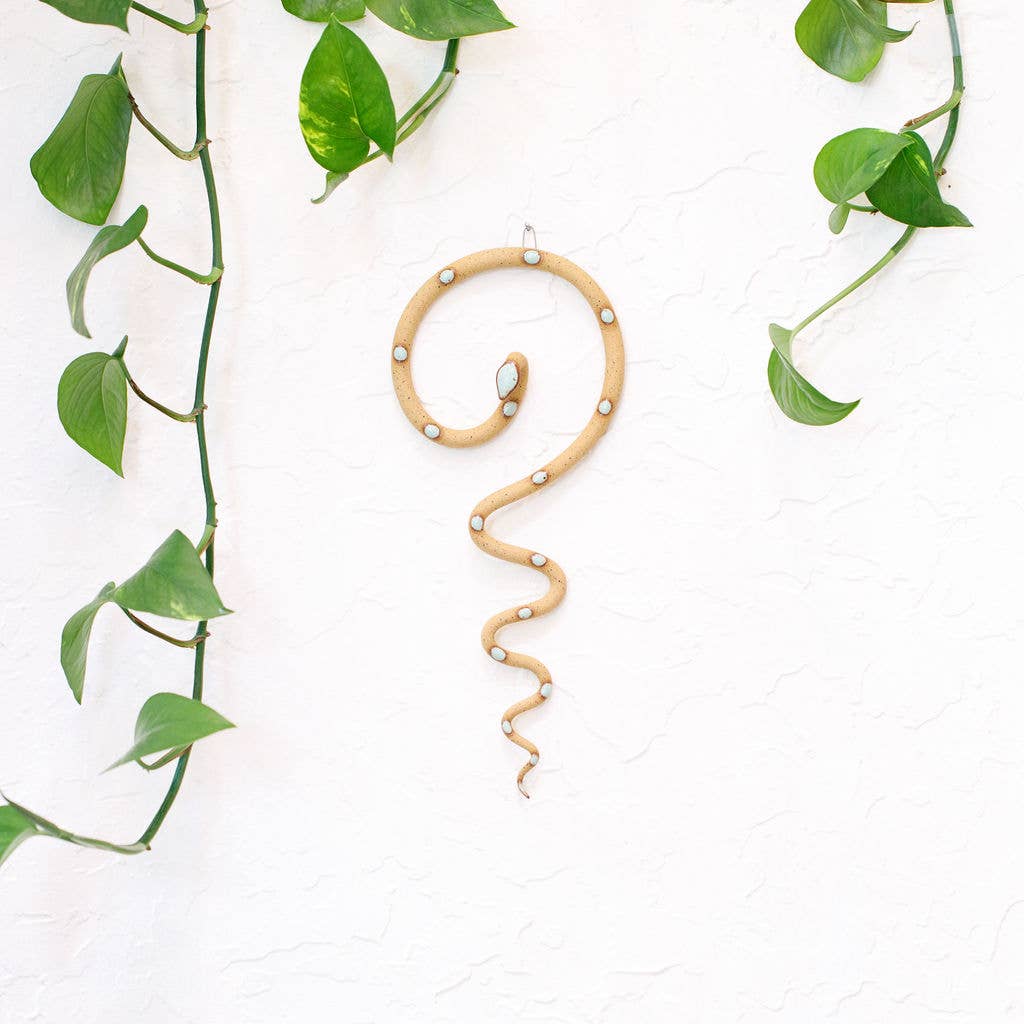 
                  
                    Ceramic snake art hanging on a wall in light brown with minty green 
                  
                