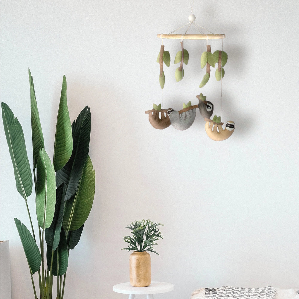 
                  
                    Felt crib mobile with four hanging sloths in a baby's room
                  
                