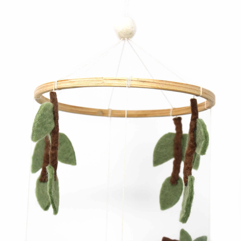 
                  
                    Close up of leaves and natural wood frame on felt crib mobile
                  
                