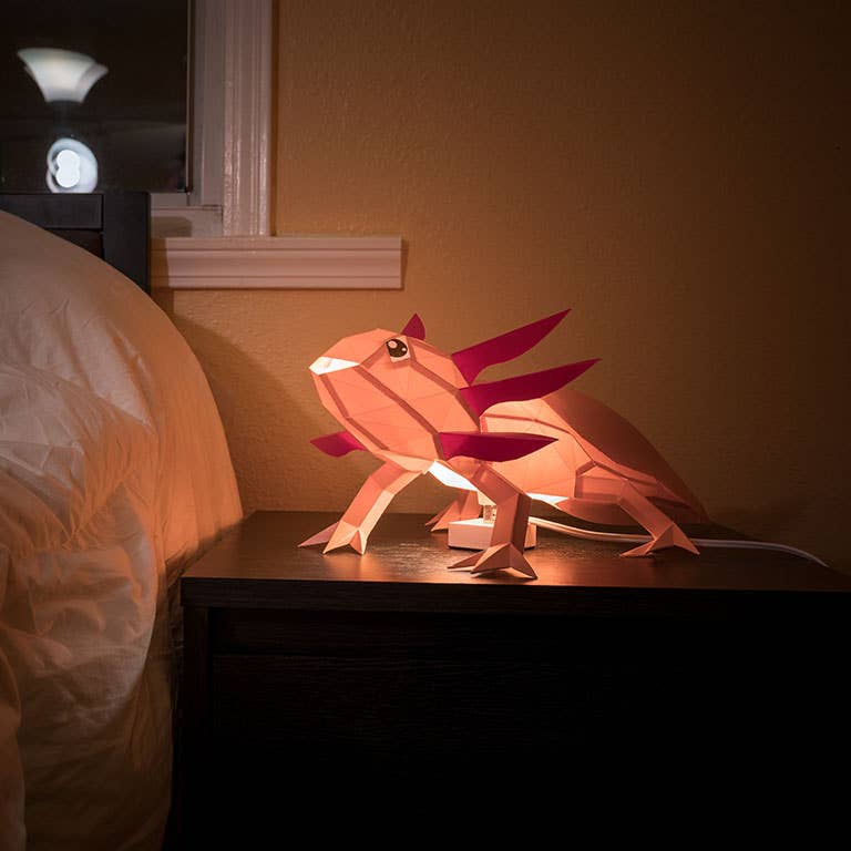 Glowing kirigami paper axolotl lamp resting on a bedside table