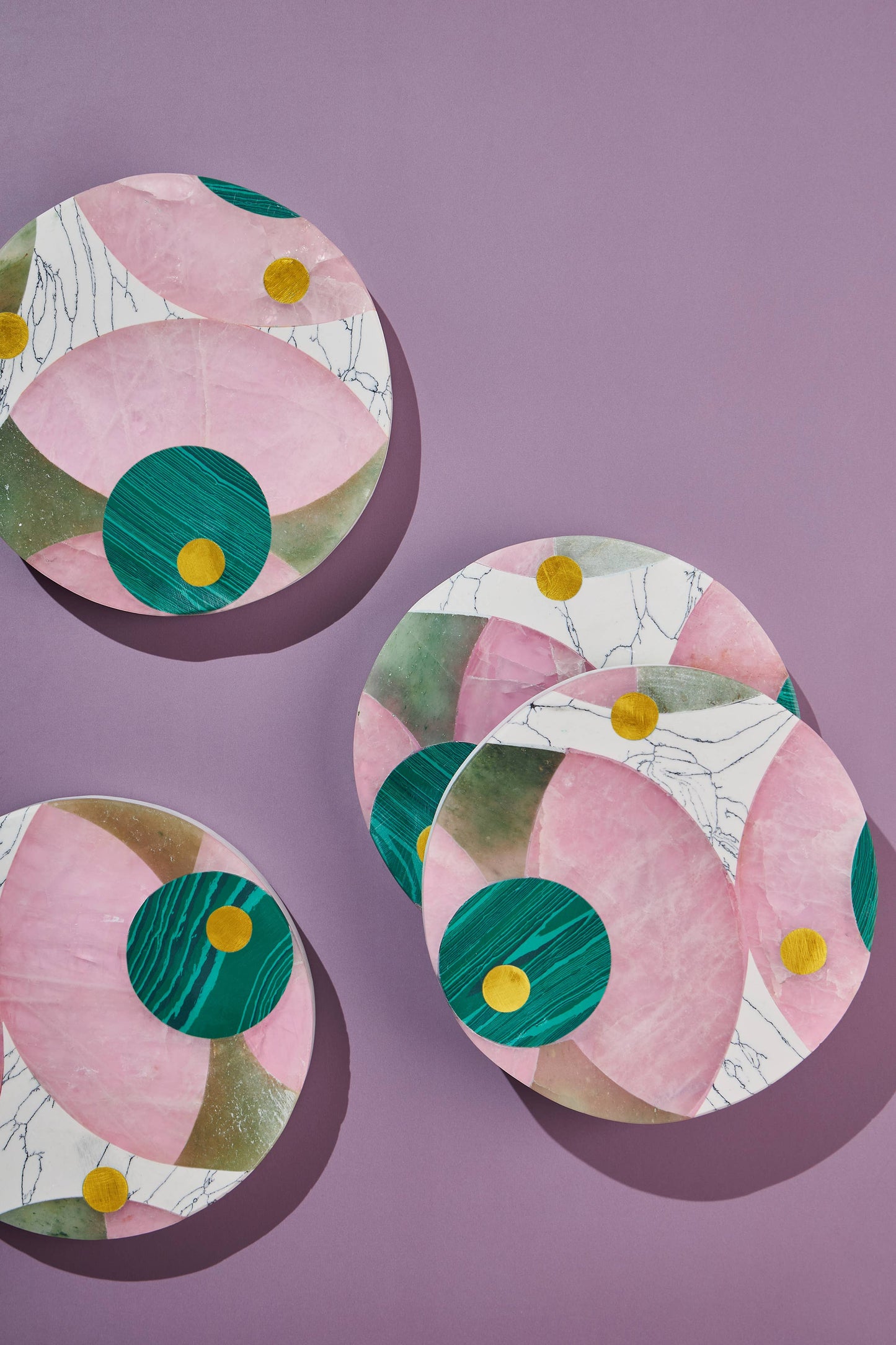 
                  
                    Four vibrant marble coasters with jade, rose, and light green marble panels and brass inlay
                  
                