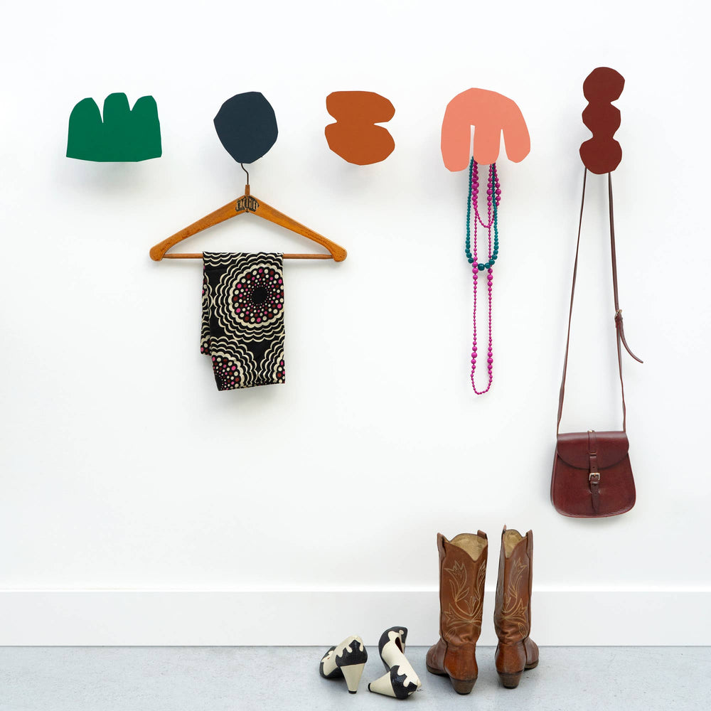 A collection of metal Matisse-inspired wall hooks in a variety of shapes and solid colors