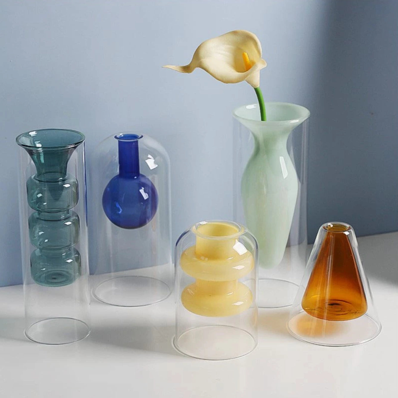 Nordic glass vase collection in transparent and opaque colors and various two-layer geometric shapes, with a colored layer hidden below smooth clear glass