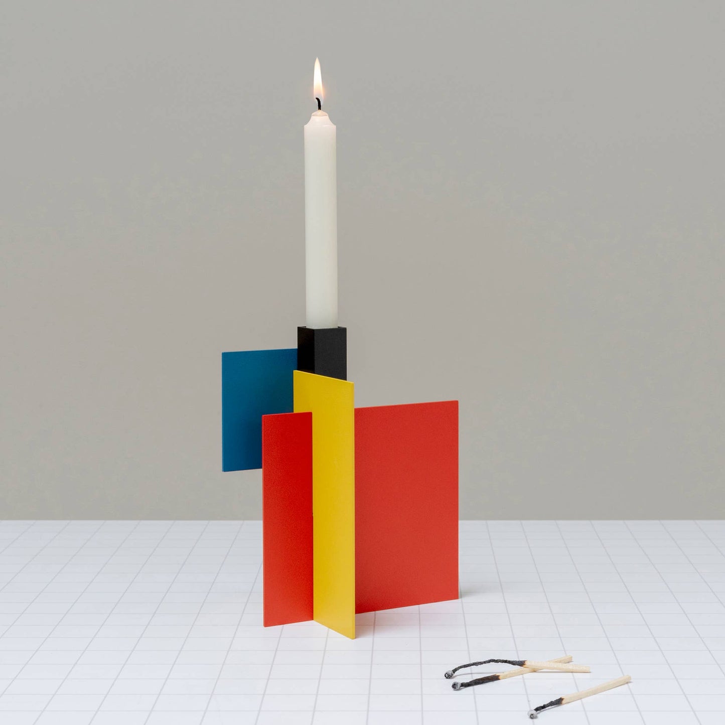 
                  
                    A sturdy metal candlestick holder in bold modern color block
                  
                
